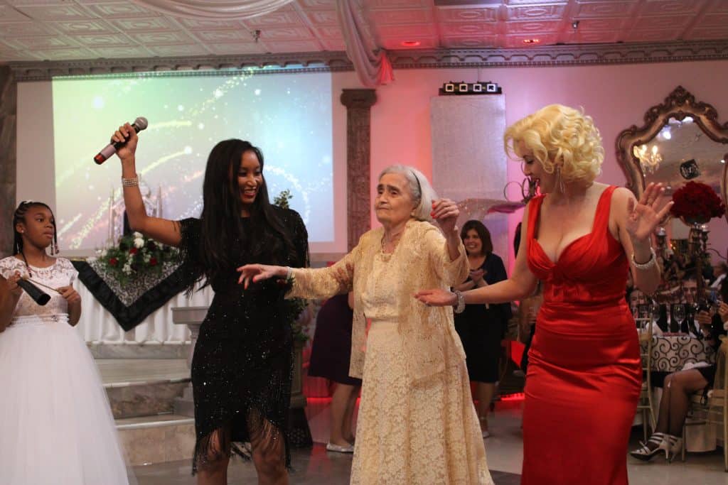 Deanna L. Giron - Singer & Pianist, an elderly woman, and a Marilyn Monroe impersonator perform on stage