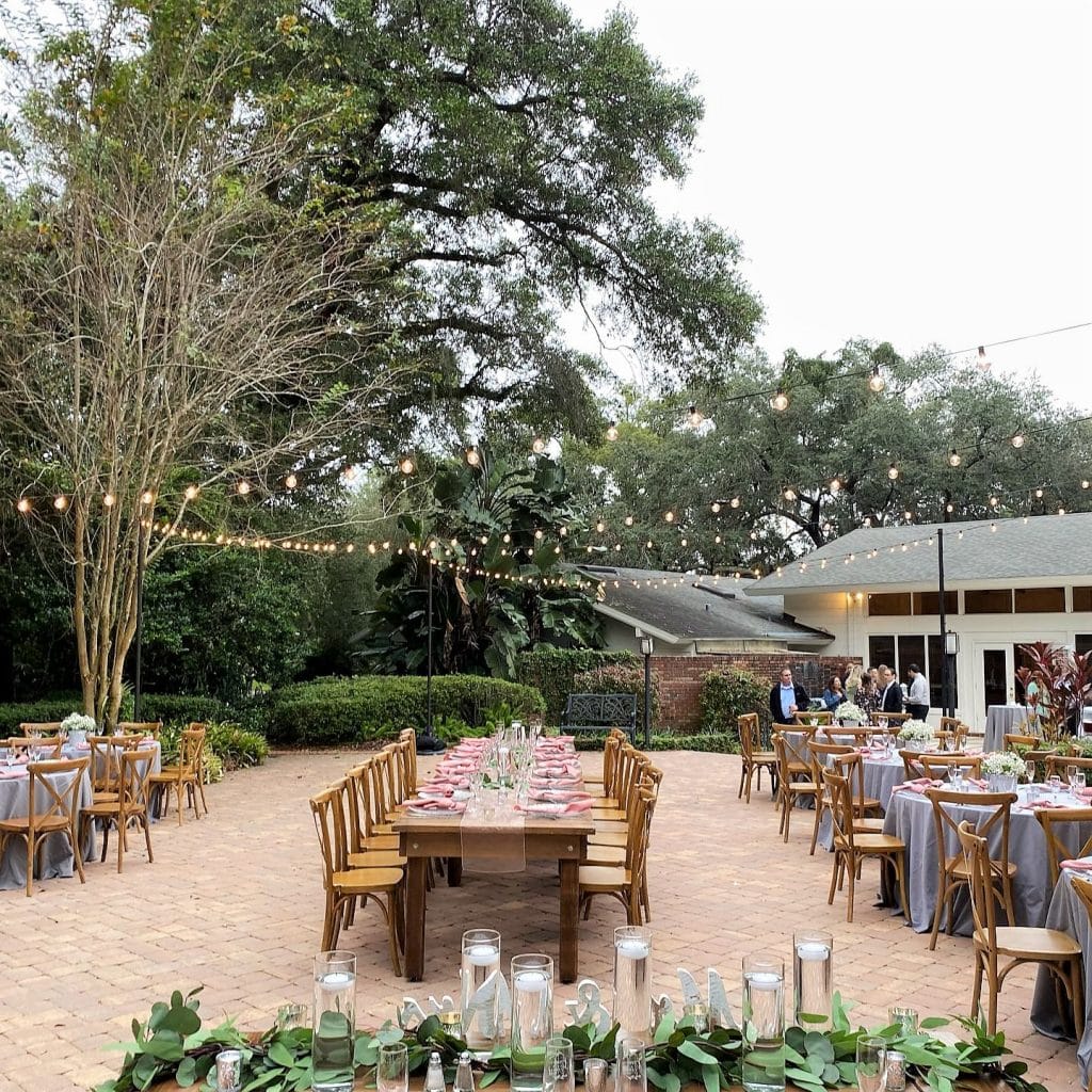 outdoor reception courtyard with long tables and round tables with grey tablecloths at The Garden Villa