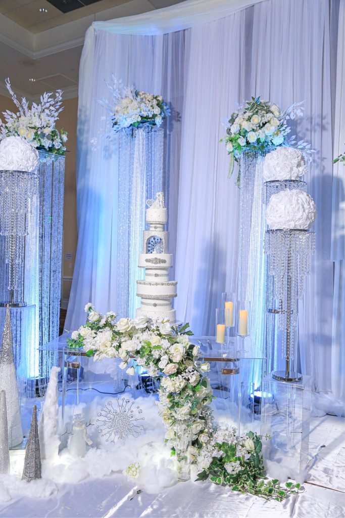 wedding cakes on glass pillars draped with white florals by Cake & Bake