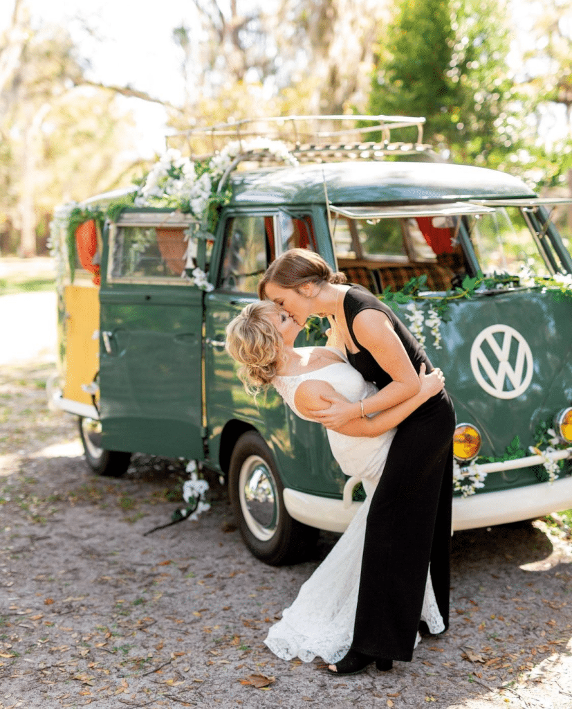 brides kissing in front of vintage Volkswagon bus at The Garden Villa