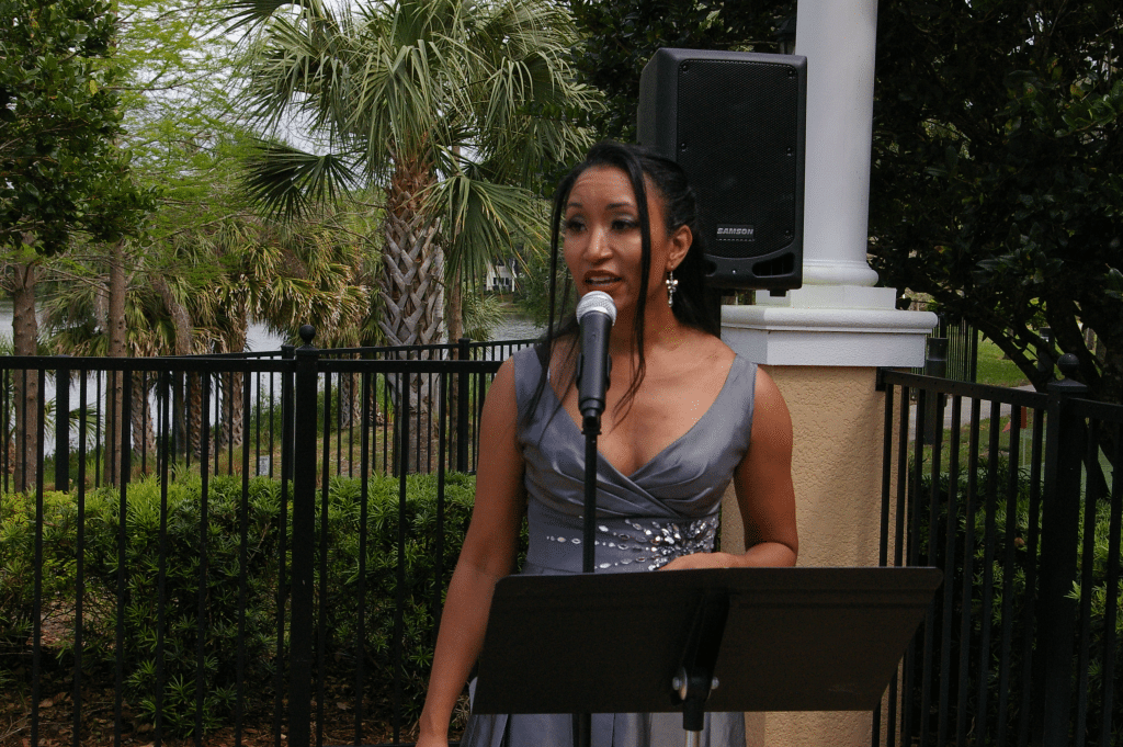 A woman , Deanna L. Giron - Singer & Pianist, sings for an event