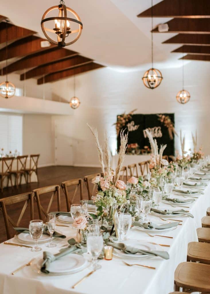 long wooden trestle tables with wooden chairs under wooden beams for wedding reception at The Garden Villa