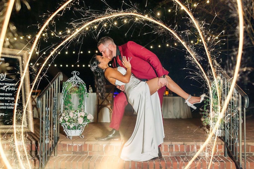 groom dipping bride under sparkler arc and market lights at The Garden Villa
