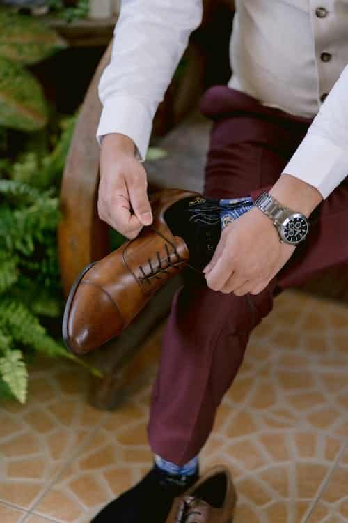 Groom ties his brown wedding day shoes