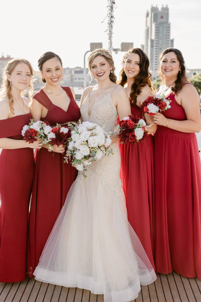 bride with bridesmaids in red and all have hair and makeup by Marci Knuth Hair And Makeup LLC