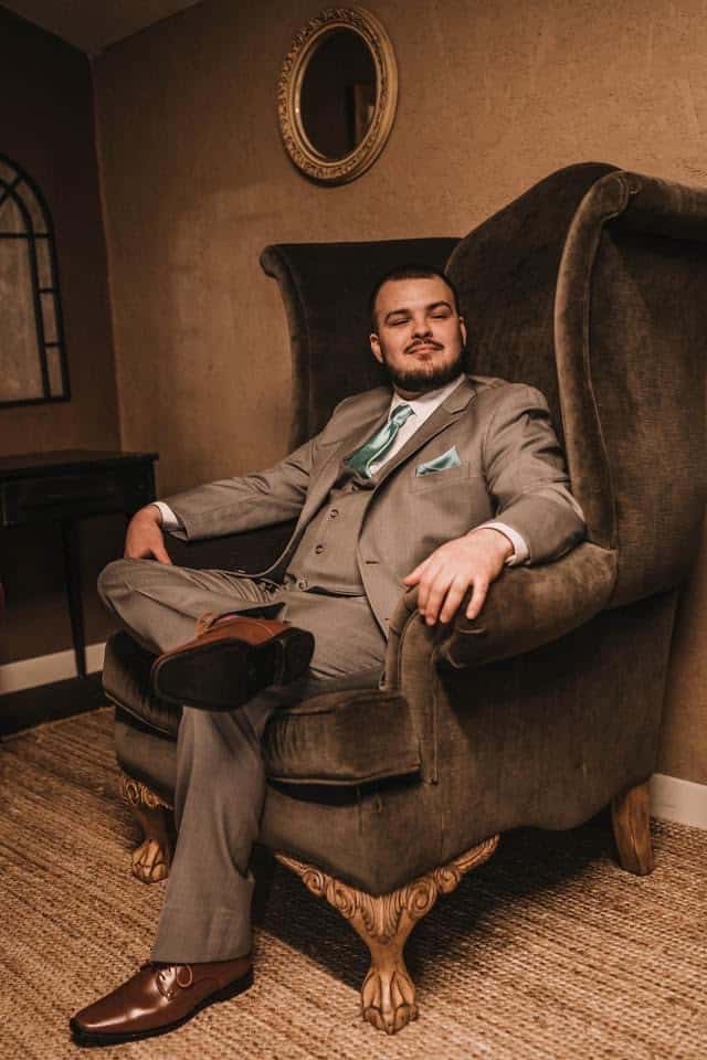 gentleman groom sitting in wingback chair at the Rocking L Ranch Wedding Barn