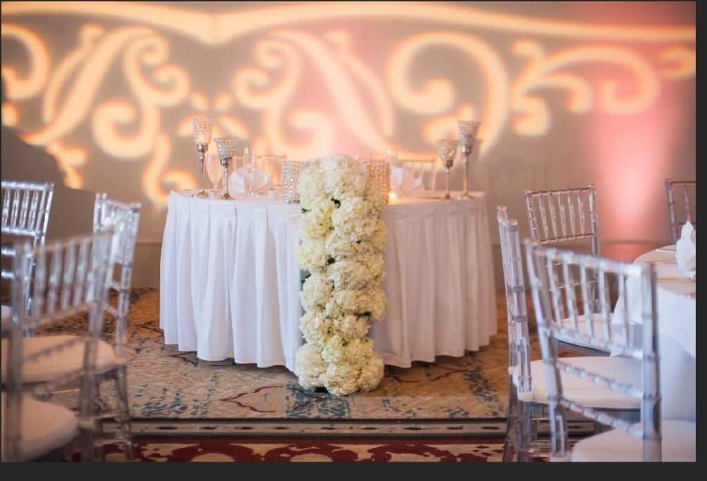 sweetheart table and filigree light swirl on wall behind it coordinated by glameventdesigns