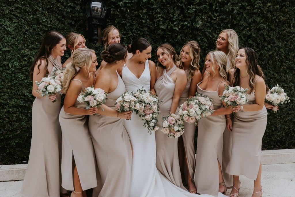 bride and bridesmaids in neutrals holding cascading bouquets by Dream Design Florist