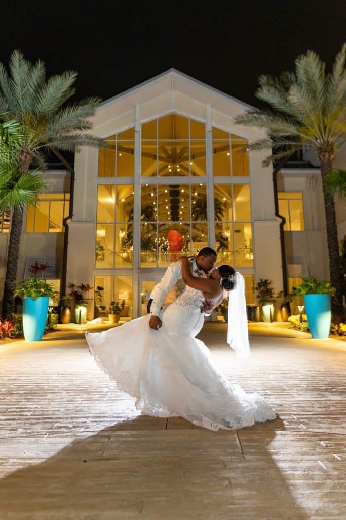 groom dipping bride with lit up building in the background coordinated by glameventdesigns
