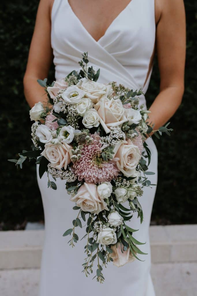bride holding cascading bouquet of pink and white flowers from Dream Design Florist