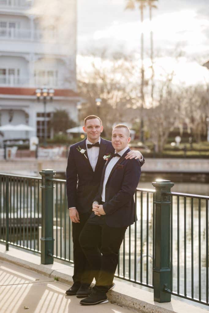 Grooms sharing a hug on a bridge photographed by Ashley Jane Photography