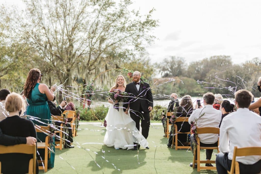 outdoor wedding with bride and groom having streamers shower them photographed by Ashley Jane Photography