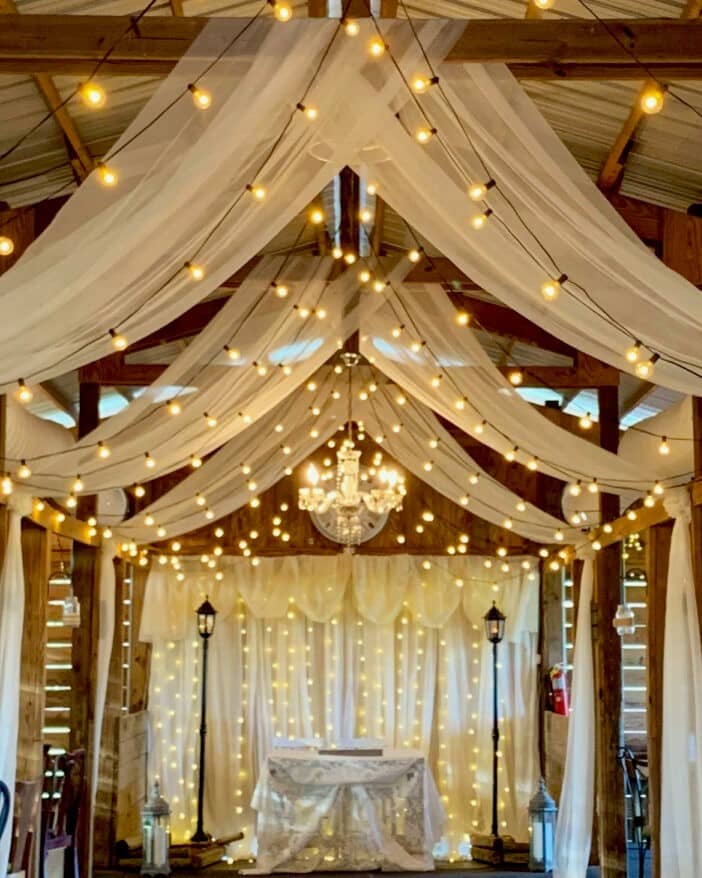 at the Rocking L Ranch Wedding Barn draped wooden beams with market lights and swag