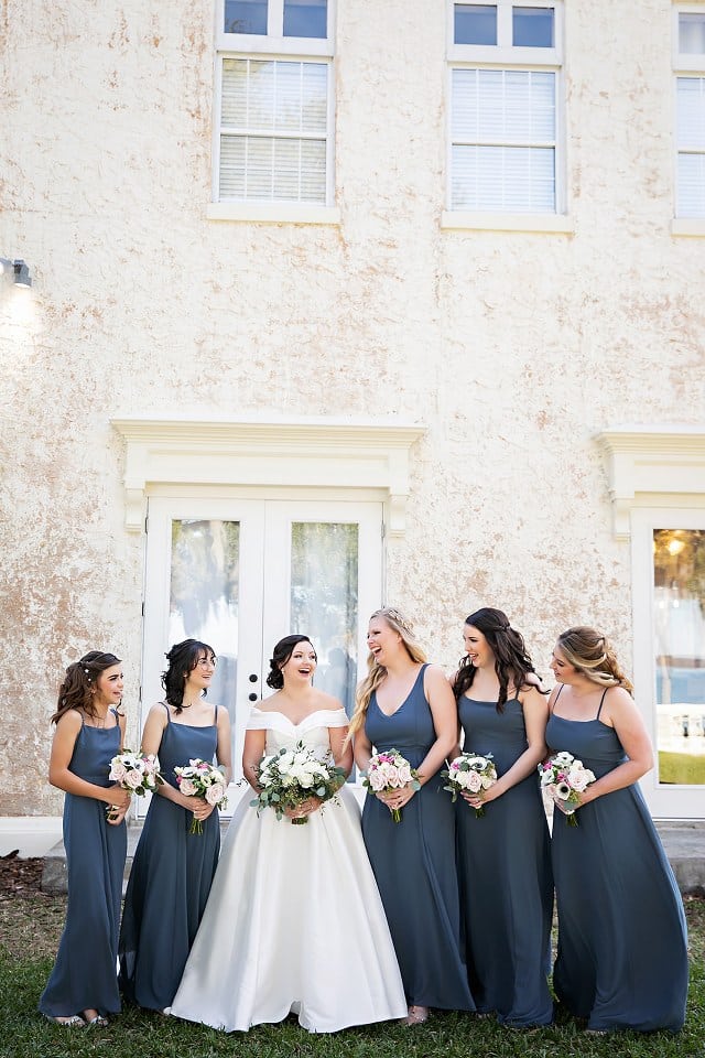 bride with bridesmaids in charcoal dresses holding pink and white floral bouquets by Dream Design Florist