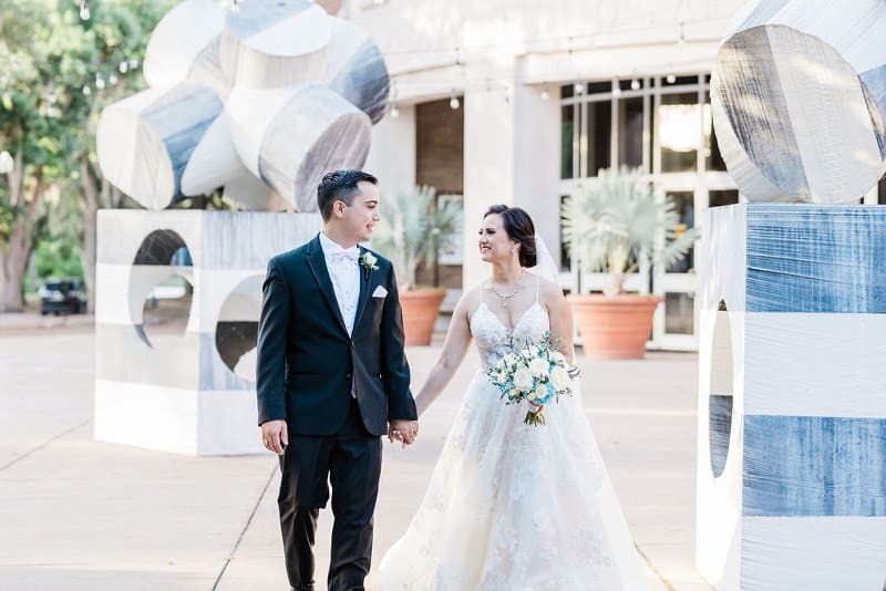 bride and groom walking through outdoor garden of modern sculptures