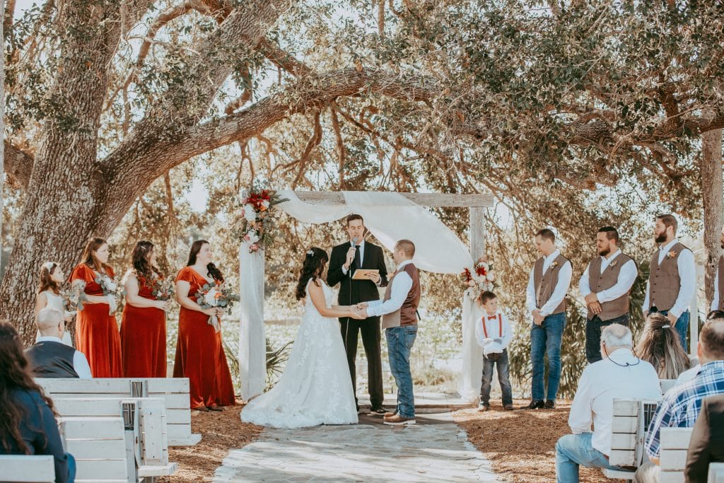 bride and groom taking their vows under canopy of oaks at the Rocking L Ranch Wedding Barn