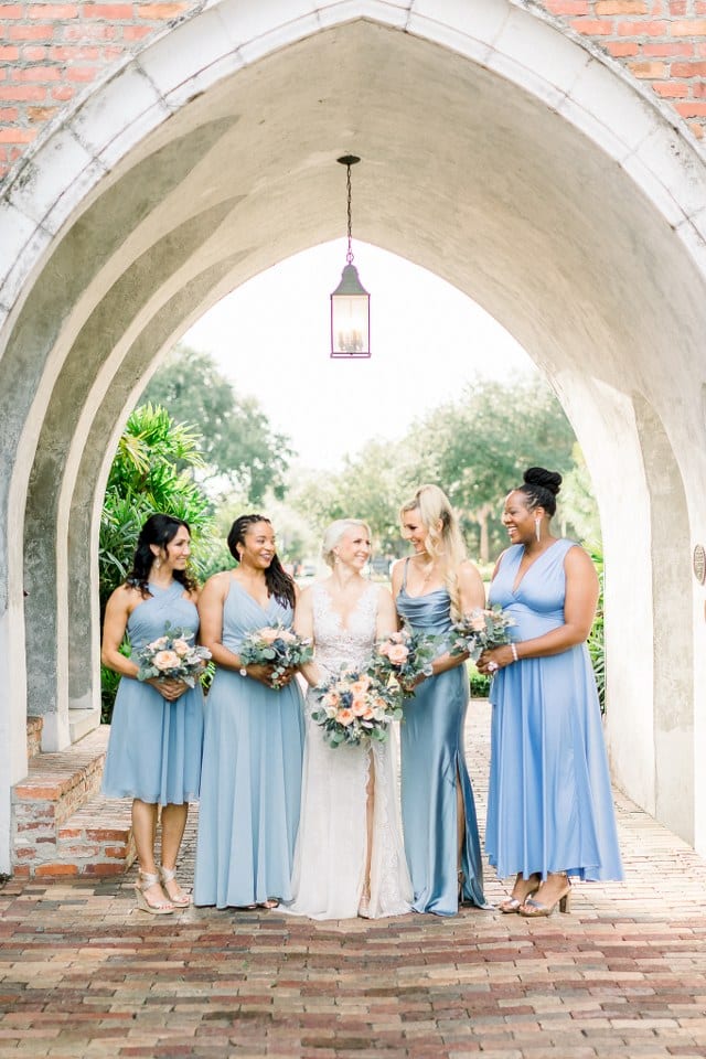bride holding bouquet of pink and white flowers with bridesmaids in pale blue holding bouquets of mixed flowers by Dream Designs Florist