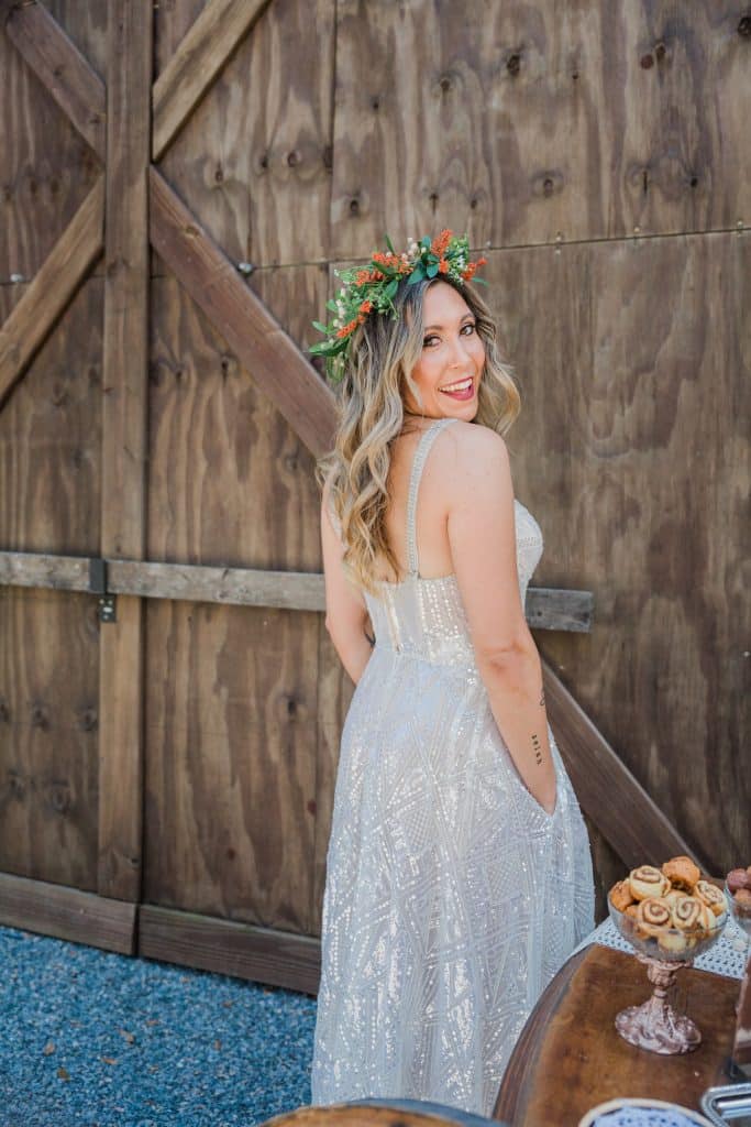 bride standing against wooden barn doors with boho flower wedding wreath in hair by Marci Knuth Hair And Makeup LLC