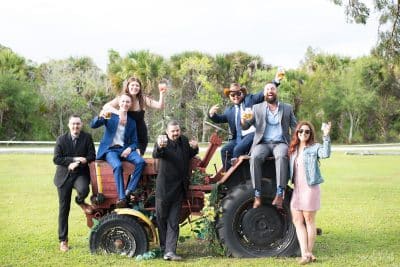 wedding party sitting on an old tractor at the Rocking L Ranch Wedding Barn
