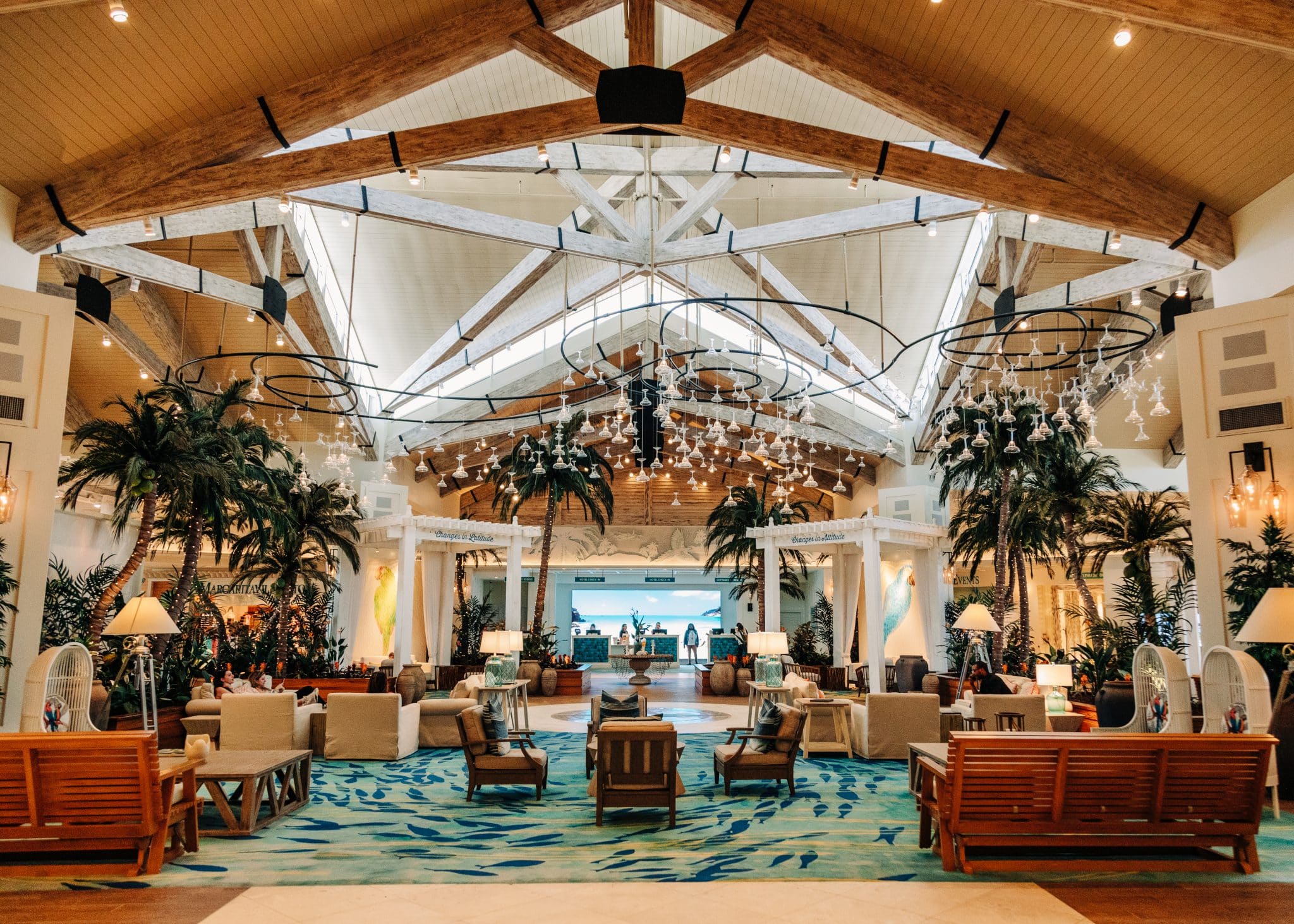 lobby picture of margaritaville resort orlando with palm trees and market lights with large sky light window in the middle and couches and chairs setup