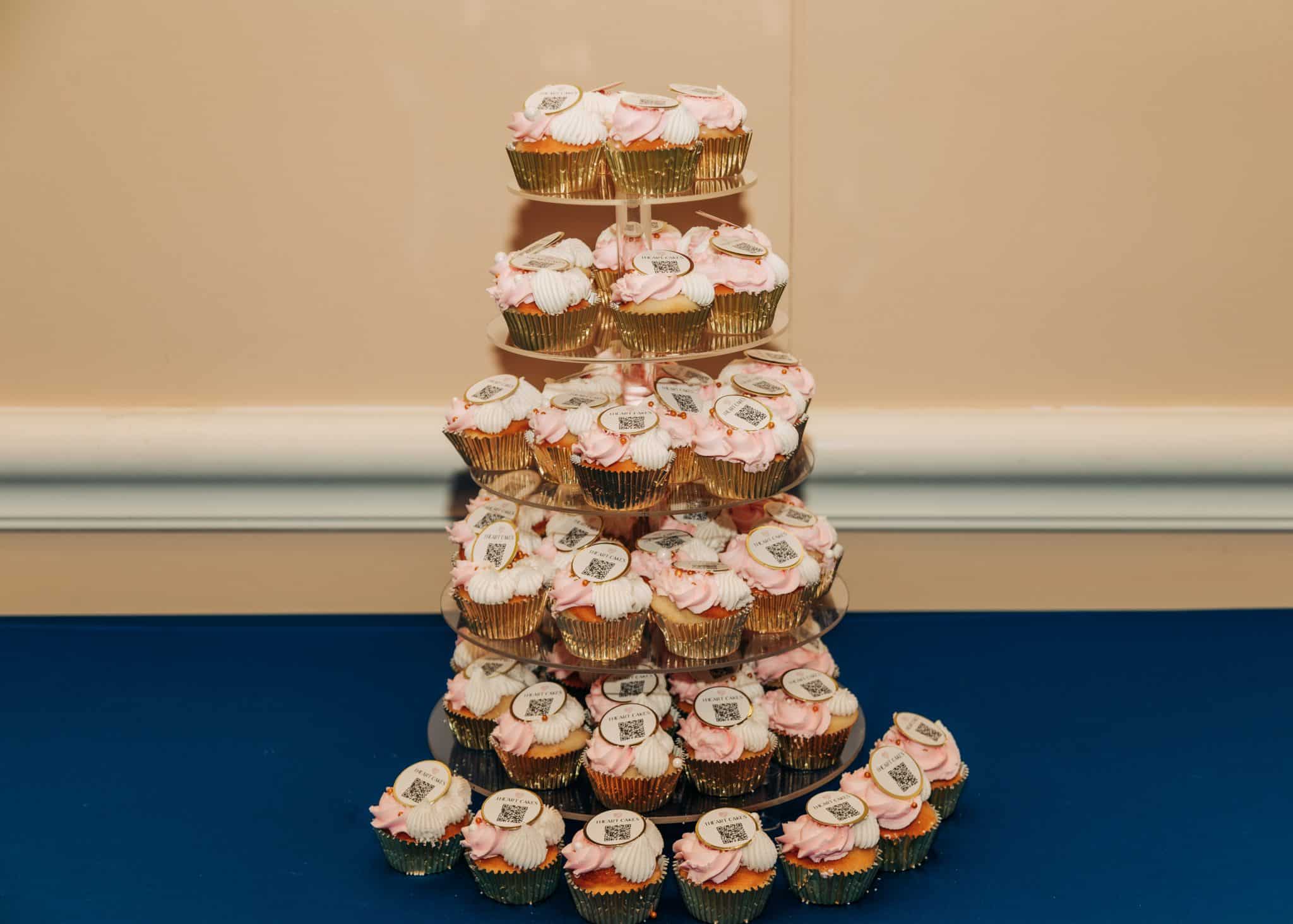 pink and white cupcakes stacked on tower on top of blue surface
