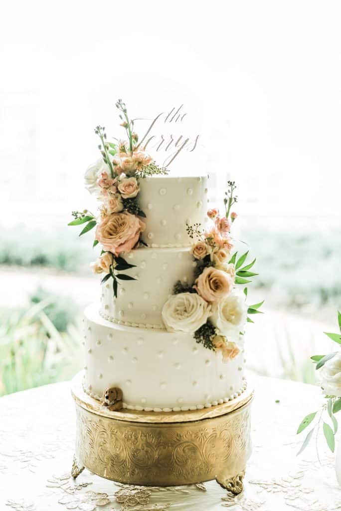 wedding cake with gold accents and pink and white peonies from Dream Design Florist