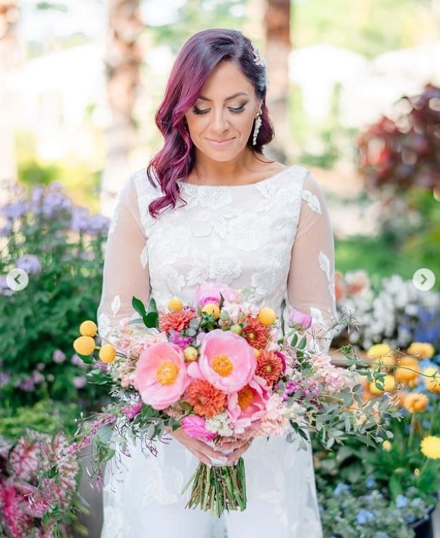 bride in colorful spring garden holding bouquet of ombre pink flowers by Dream Design Florist