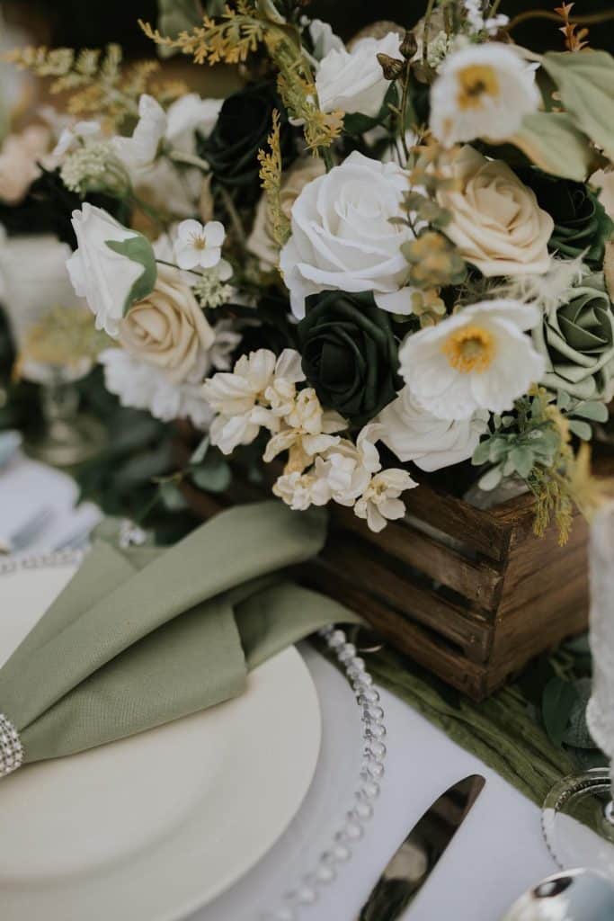 table setting with sage accents and white flowers at wedding planned by The Lainey Rose