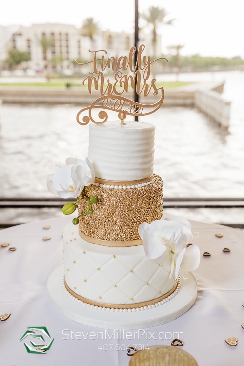 gold and white wedding cake in window looking out at the water at 520 on the Water