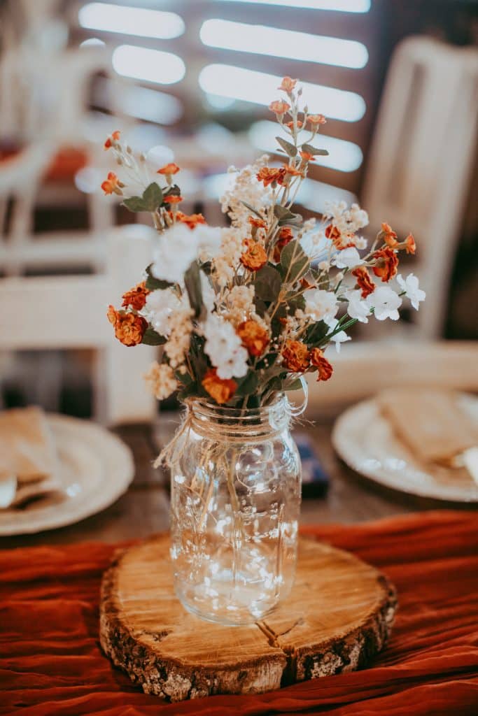 mason jar filled with flowers on a wooden trivet at the Rocking L Ranch Wedding Barn
