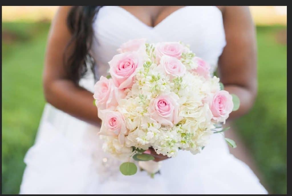 torso photo of bride holding delicate bouquet of pink and white flowers at wedding coordinated by glameventdesigns