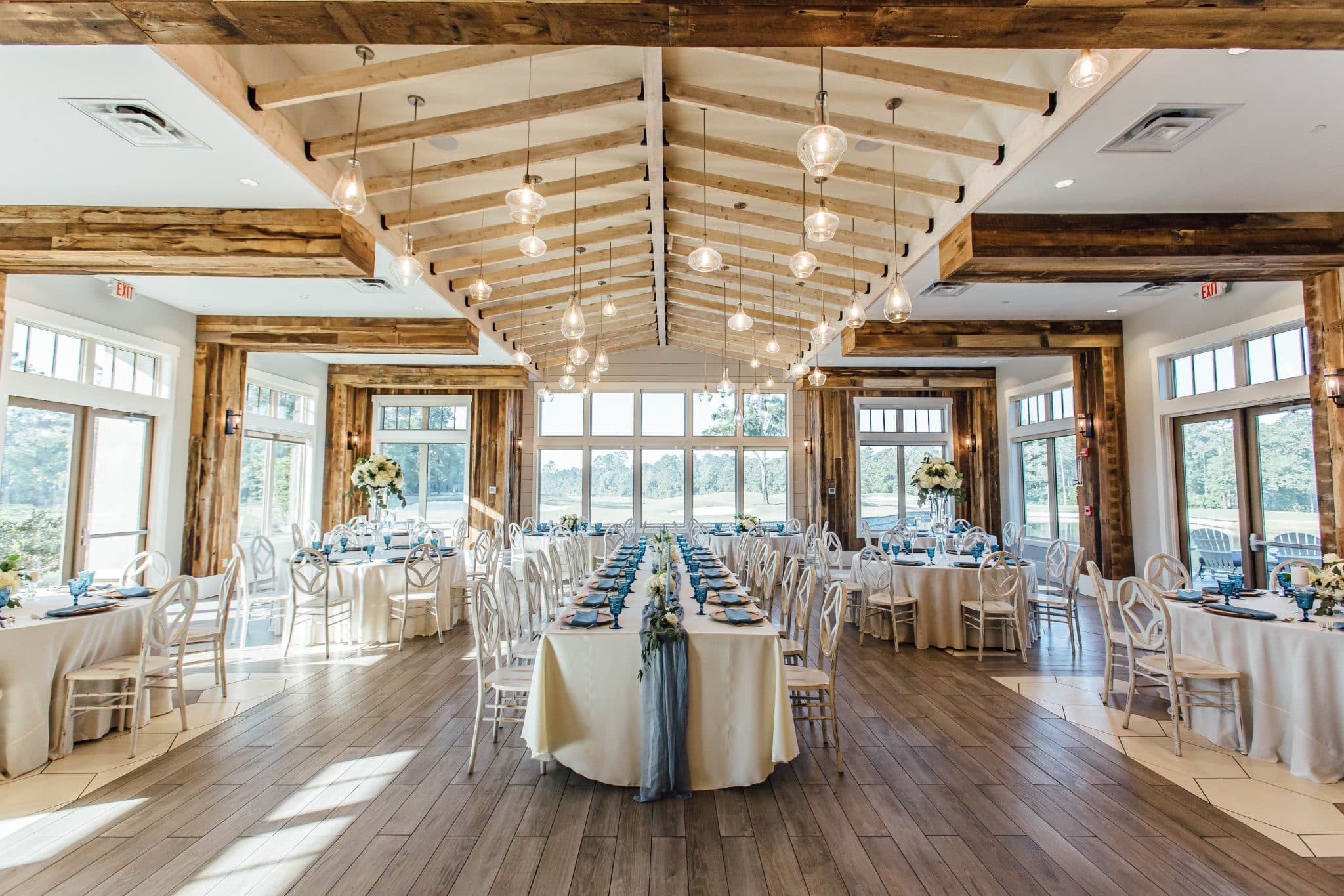 long tables set with turquoise and gold accents at daytime reception in ballroom with glass walls at St. Johns Golf & Country Club