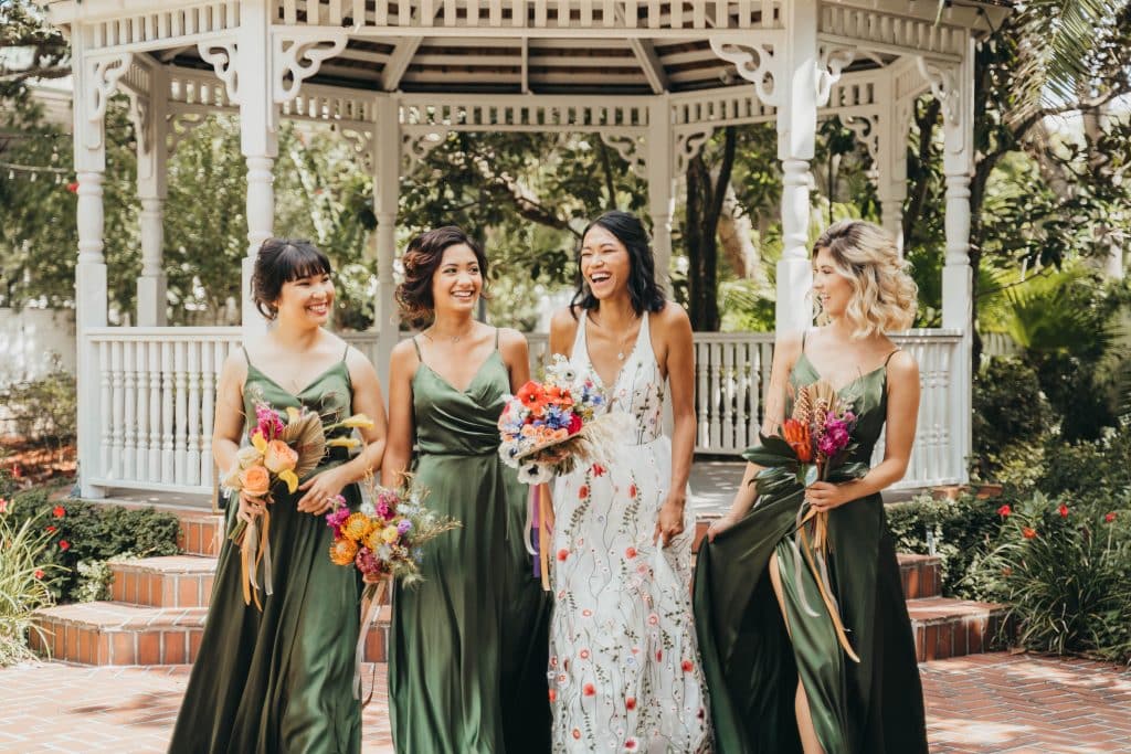 bride in floral dress and bridesmaids in sage green with natural hair and makeup by Marci Knuth Hair And Makeup LLC