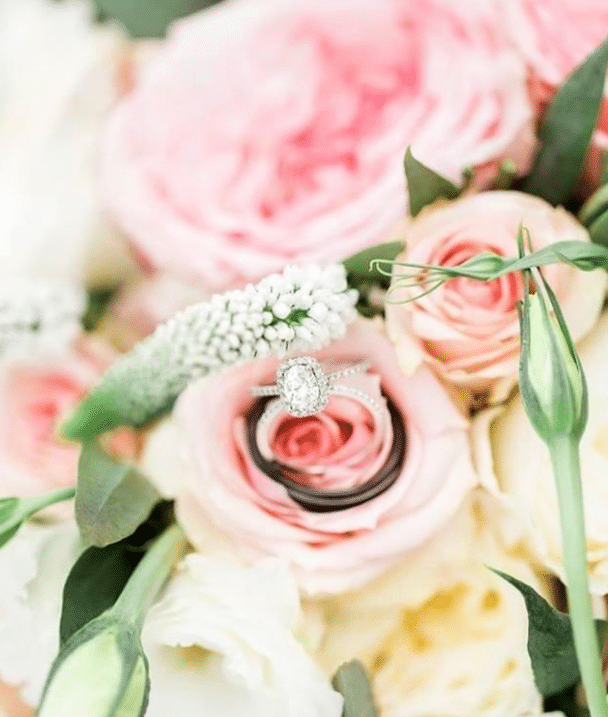 Stunning engagement ring nestled in the bed of a pink rose, surrounded by additional flowers in Orlando, FL