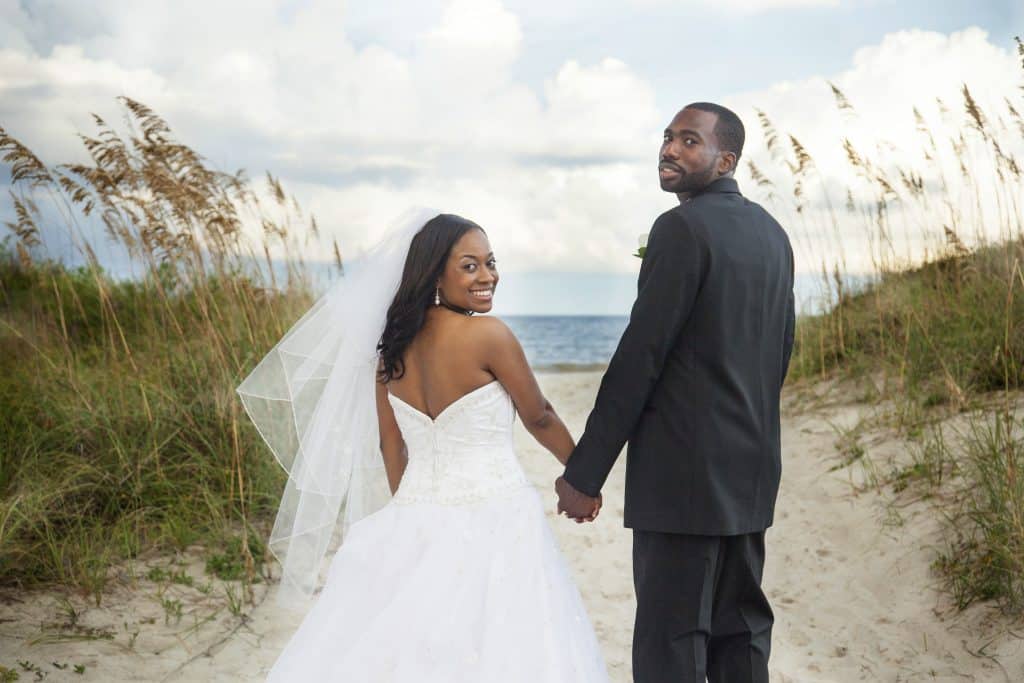 bride and groom walking through the dunes by Evan Hampton Photography