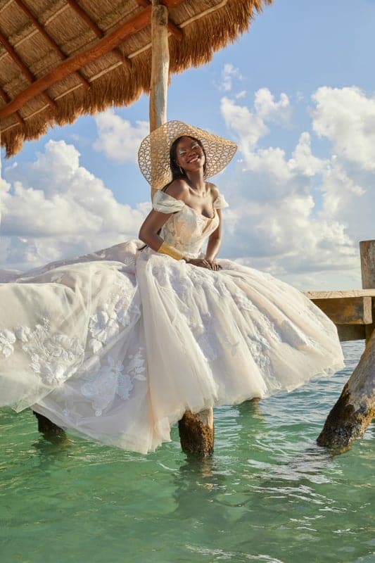 beautiful island bride on a pier with blue water wearing wedding gown from Lily’s Bridal