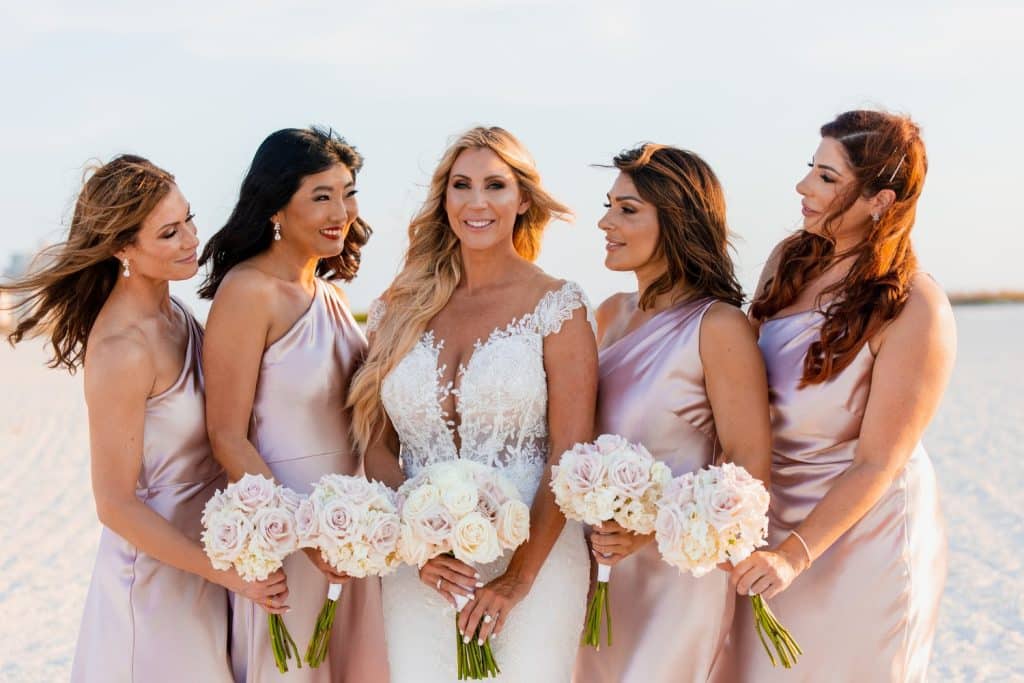 bridesmaids in pink and bride on beach photographed by Slone Photography, LLC