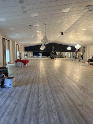 Spacious ballroom being decorated for a holiday party with a christmas tree and red overlays on white tablecloths, Central, FL