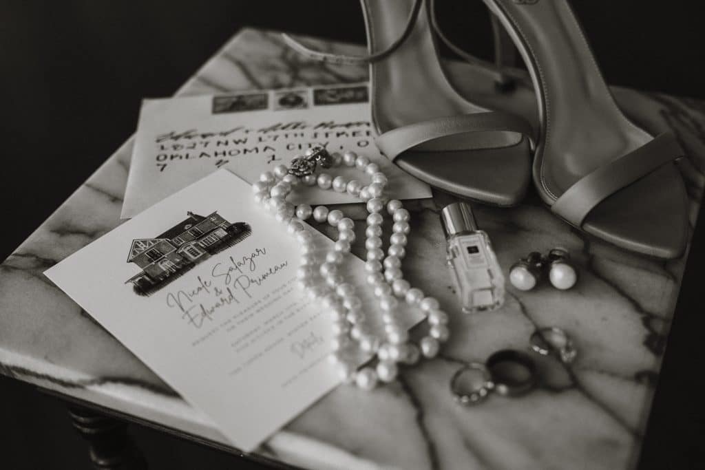 wedding details flatlay including invitation, jewelry and wedding shoes