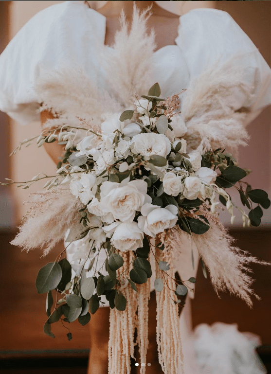 White floral bouquet with greens and feathers, held by a bride in a white gown, Orlando, FL