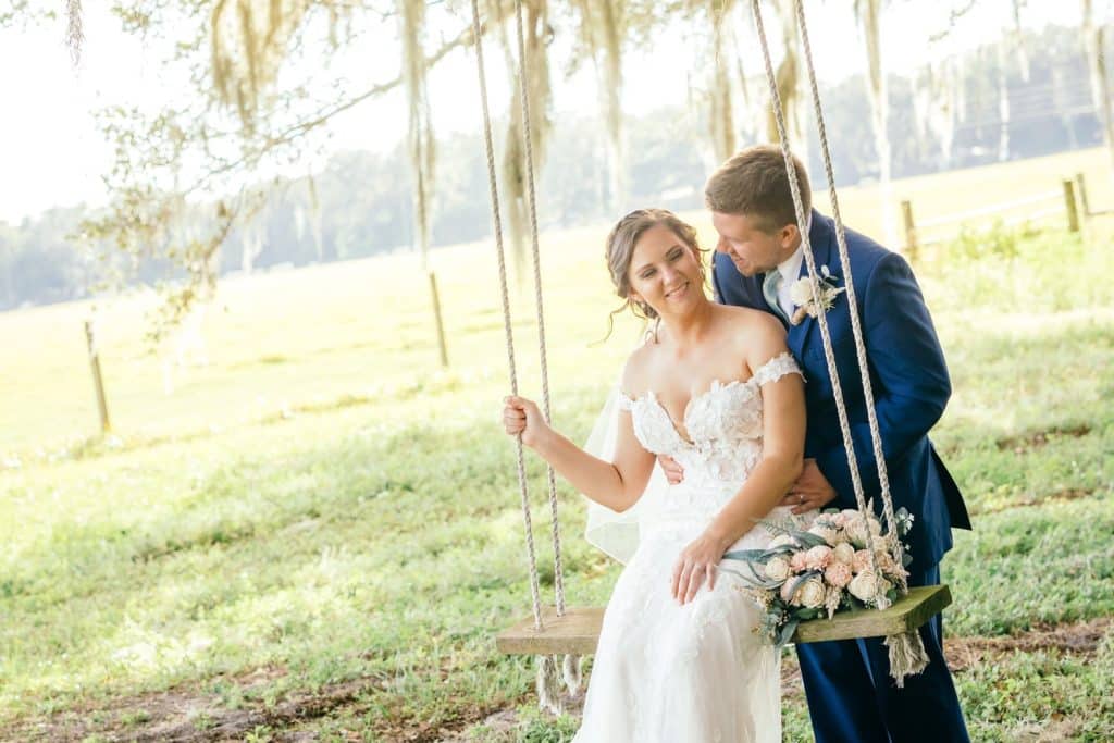 groom pushing bride on a rope swing with flower decor photographed by Slone Photography, LLC