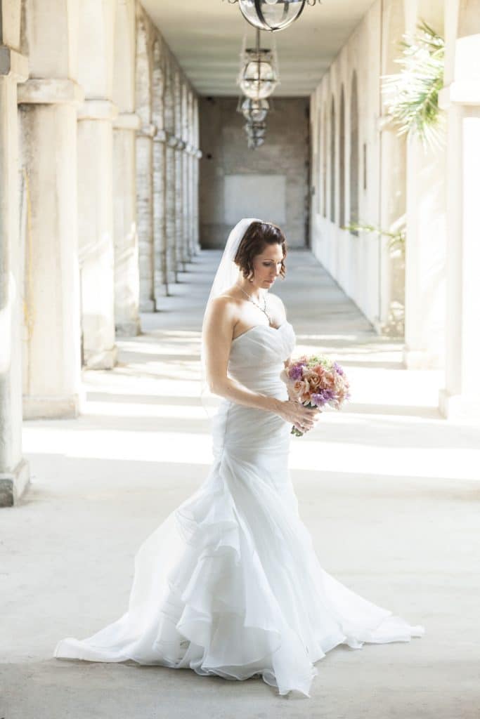 bride standing at the end of a long hallway of pillars by Evan Hampton Photography
