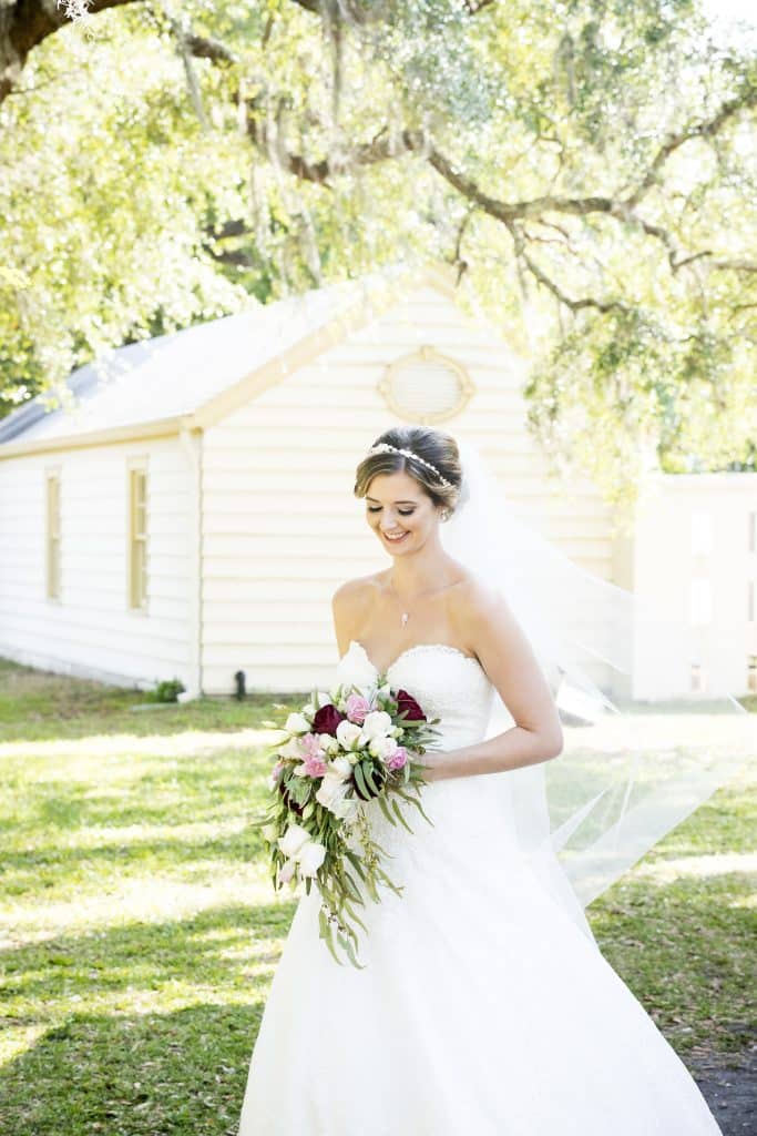 bride outdoors under a tree by little white chapel by Evan Hampton Photography