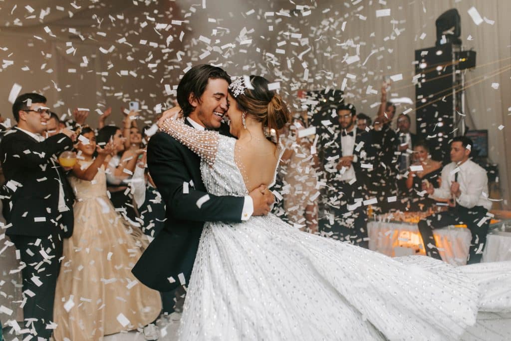 bride and groom dancing under white confetti by Elite Celebrations