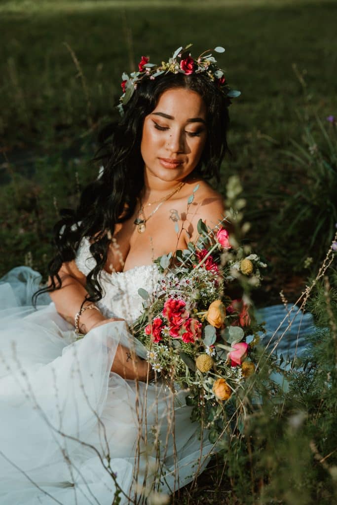 Bride sitting in the grass with her bouquet and floral crown on her wedding day in Orlando, FL