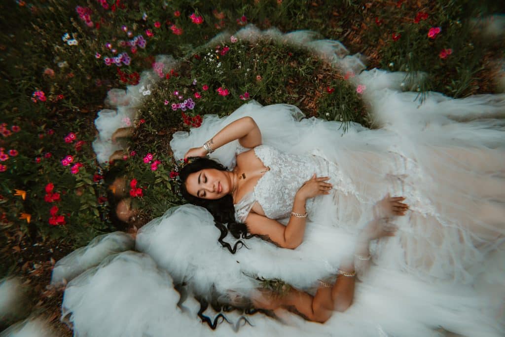Bride laying in the grass surrounded by a variety of flowers in a circular design in Orlando, FL