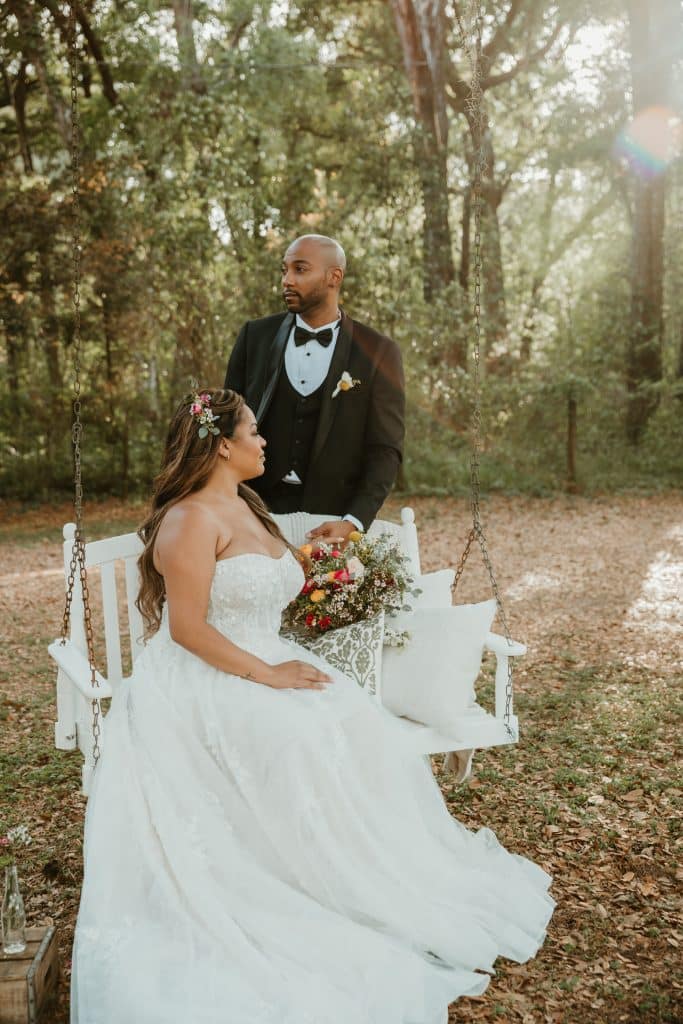 Groom standing over his bride in the woods, both staring into the distance in Orlando, FL.