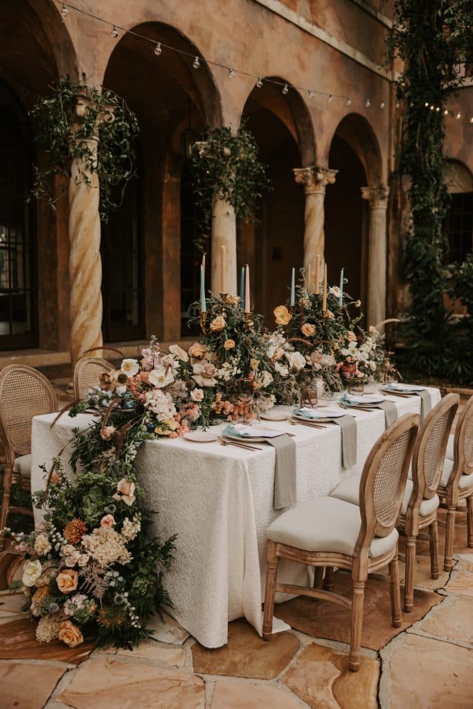 table set with opulent floral centerpiece from In Bloom Florist draping to the ground