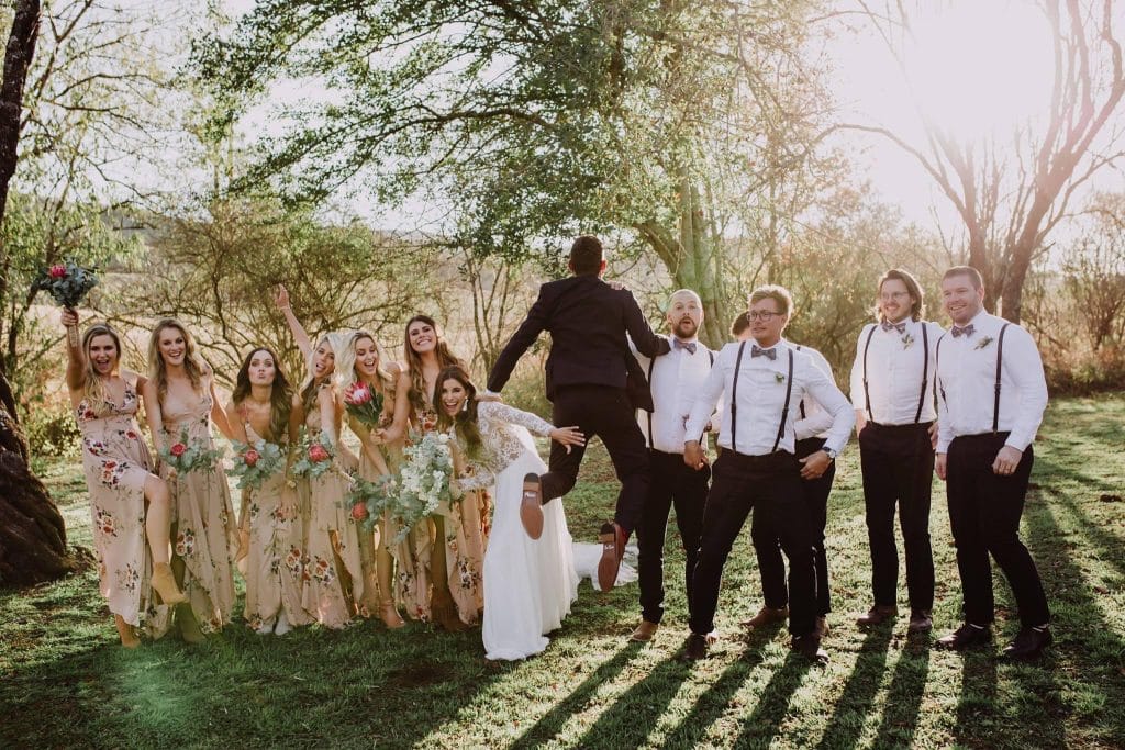 groom jumping for joy with bridal party laughing at wedding coordinated by A. Marie Events & Design