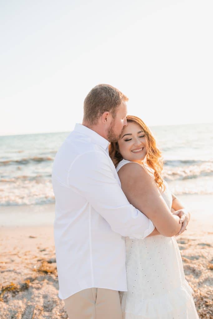 newly engaged couple smiling on the beach photographed by Slone Photography, LLC